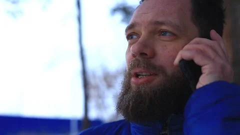 Bearded man talking on the phone after training and walking in the park on a win Stock Footage 99603600