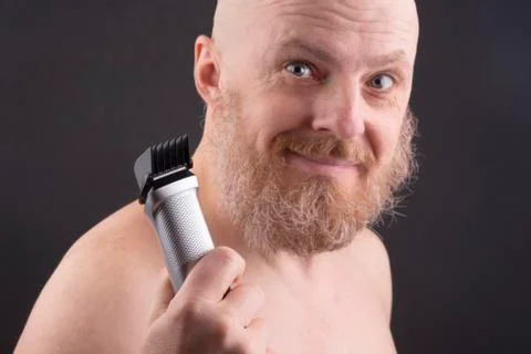 Bearded man with trimmer to adjust beard in hand Stock Photos