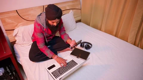 Bearded man types on laptop and plays clips by mobile Stock Footage 312381041