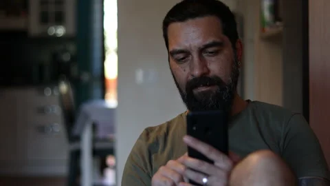 Bearded man typing on smartphone while resting on sofa in living room. Stock Footage 156756149