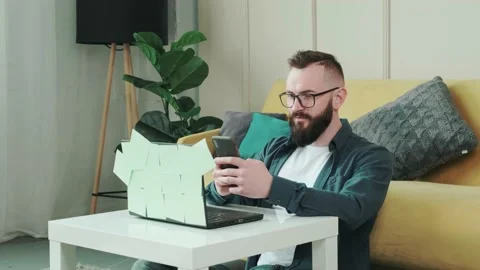 Bearded man typing a sms to his friend while is taking a break from working Stock Footage 155759996