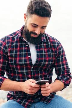 Bearded man typing a text message on his phone Stock Photos