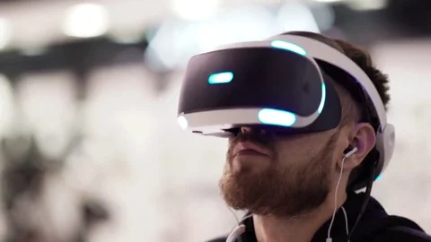 Bearded man uses VR-headset display with headphones for virtual reality game Видео 69124419