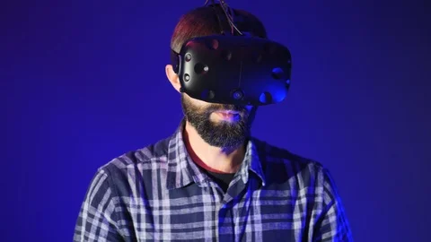 Bearded man uses VR-headset display for virtual reality video game in vr club Stock Footage 99726368
