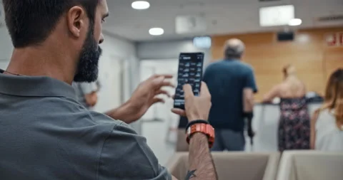 Bearded man using mobile phone while sitting at hospital lobby waiting doctor Stock Footage 143478665