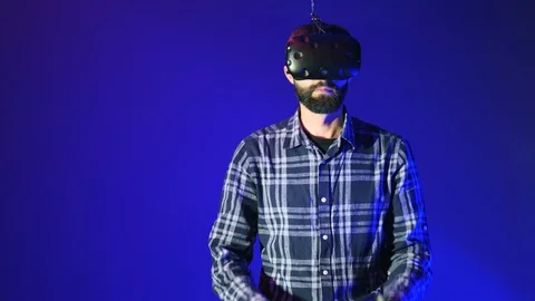 Bearded man using modern virtual reality headset with gamepad, remote Video stock 98605373