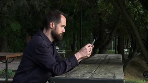 Bearded Man Using Smartphone at Outdoor Table in Subotica Park Vídeos de archivo 336178546
