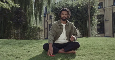 Bearded man using smartphone, putting it on ground and start meditating on grass Stock Footage 145219069