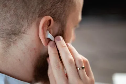 Bearded man using wireless earphones. listening to music. Close-up of earphon Stock Photos