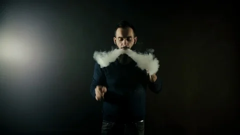 Bearded man vapes one big ring of steam with electronic cigarette in slow motion Video stock 111384240