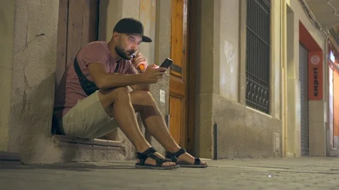 Bearded man vaping cigarette while texting on phone Stock Footage 94899493