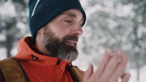 Bearded man warming cold hands in winter forest Stockbeeldmateriaal 331670576