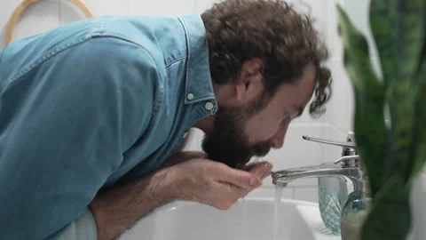 Bearded man washing his face in the bathroom sink Vídeos de archivo 336624718
