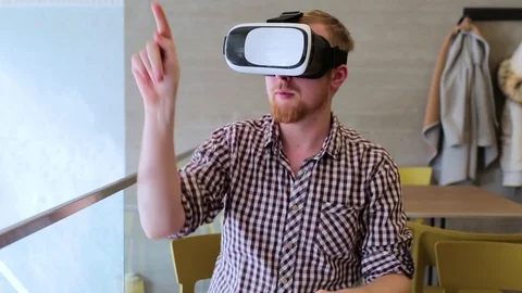 A bearded man wearing virtual reality glasses in the cafe Stockbeeldmateriaal 74443473