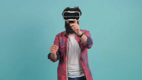 Bearded man wearing virtual reality glasses. Studio shot, turquoise background. Stock Footage 140785718