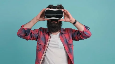 Bearded man wearing virtual reality glasses. Studio shot, turquoise background. Stock Footage 147139018