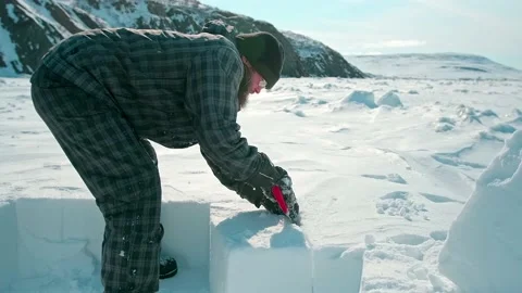 Bearded man in winter clothes cuts large snow block closeup Stock Footage 134316521