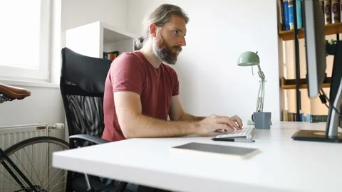 Bearded man working from his home office desk Stock Footage 130174150