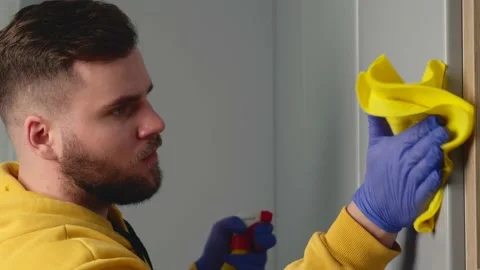 Bearded man is working at home cleaning the house using a wipe with Stock Footage 148613253