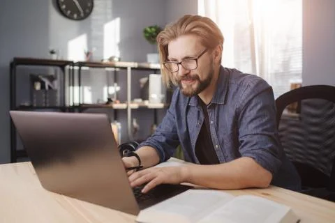Bearded man working on laptop while sitting at table Stock Photos