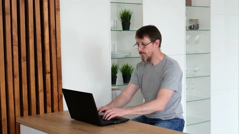 Bearded man working office work remotely from home. Fifty year old man using Stock Footage 188429823