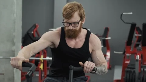 Bearded man working out on exercise bike at gym. Redhead man training on bicycle Stock Footage 108941690