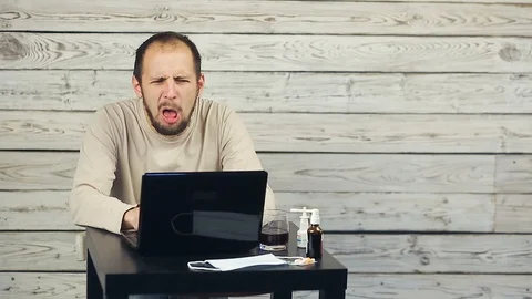 A bearded man works at the computer and coughs. 스톡 동영상 98562560