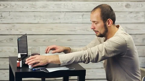 A bearded man works at the computer and coughs. Stock Footage 98565630