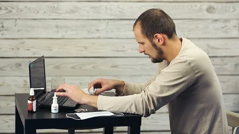 A bearded man works at the computer and coughs. Stock Footage 98566418