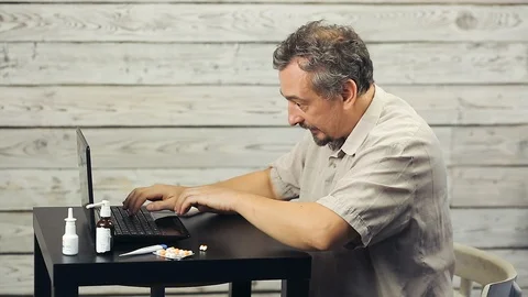 A bearded man works at the computer and coughs. Stock Footage 98759882