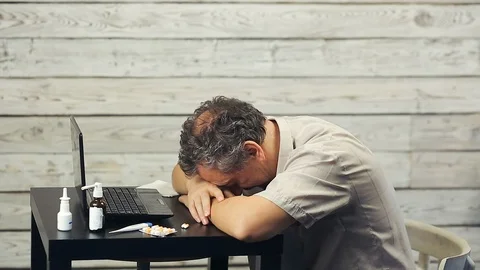 A bearded man works at the computer and coughs. Stock Footage 98760104