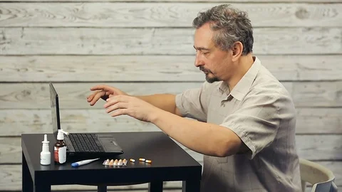 A bearded man works at the computer and coughs. Stock Footage 99882055