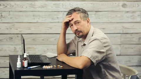 A bearded man works at the computer and coughs. Stock Footage 99882392