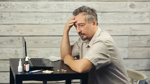 A bearded man works at the computer and coughs. Stock Footage 99883197