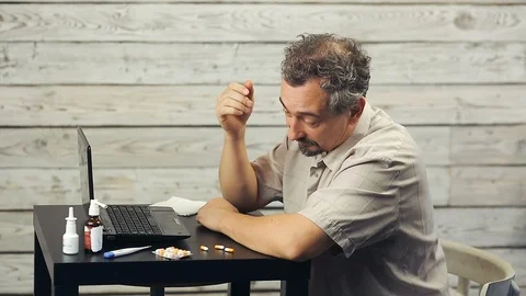 A bearded man works at the computer and coughs. Stock Footage 99883975