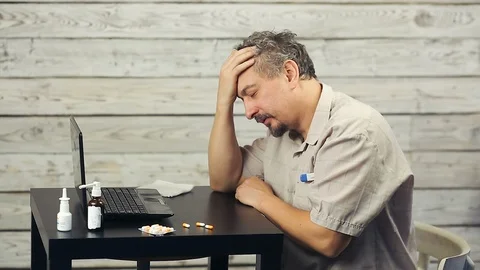 A bearded man works at the computer and coughs. Stock Footage 99941621