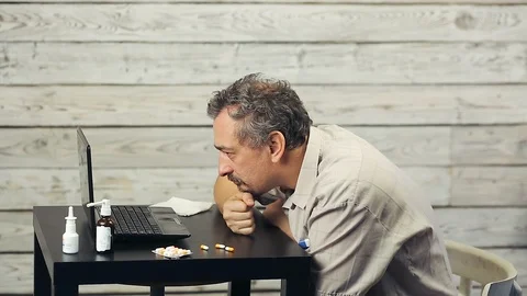 A bearded man works at the computer and coughs. Stock Footage 103487894