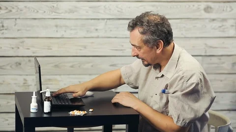 A bearded man works at the computer and coughs. Stock Footage 108202484