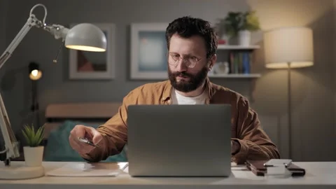 Bearded man works at computer and types. Remote worker in home office is doing Vídeos de archivo 188727727