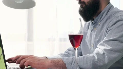 Bearded man that works at the computer full of reminder notes, drink wine. Stock Footage 153103925