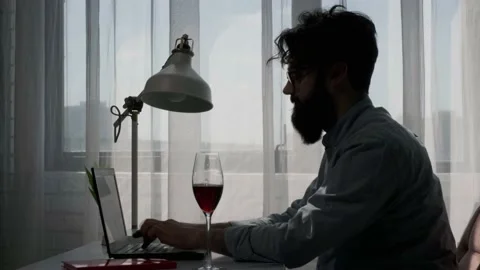 Bearded man that works at the computer full of reminder notes, drink wine. Stock Footage 155760398
