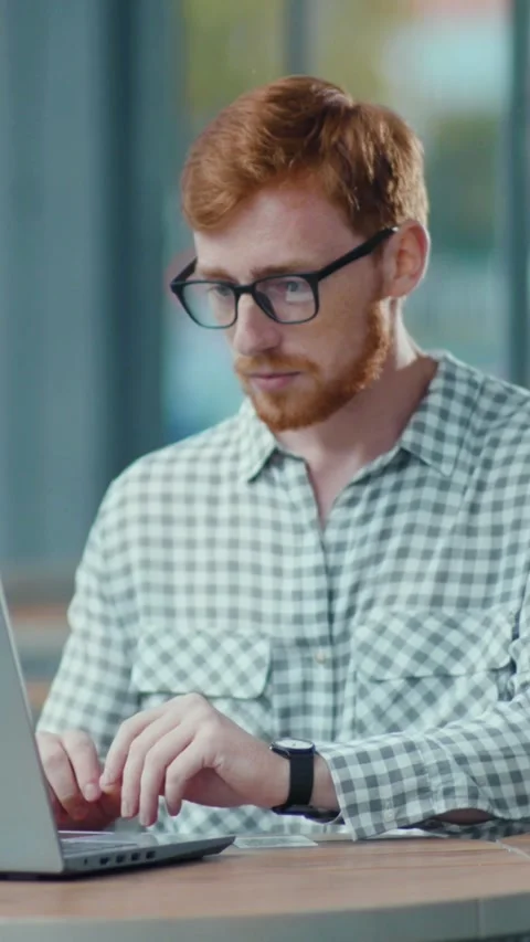 A bearded man works on his laptop in a cozy, relaxed setting Stock Footage 314963161