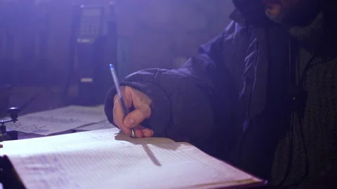 Bearded man writes in diary with pen sitting at table Stock Footage 230691838