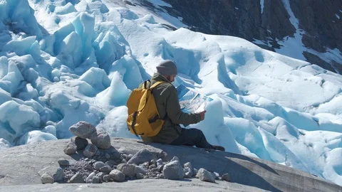 Bearded man with a yellow backpack and a tourist map in his hands, against the Stock Footage 109136256