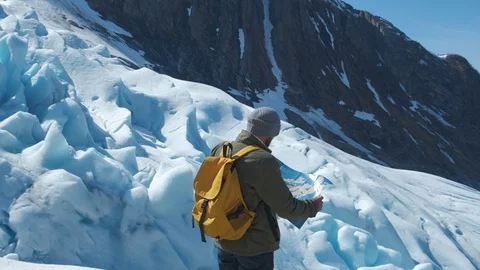 Bearded man with a yellow backpack and a tourist map in his hands, against the Stock Footage 109136333