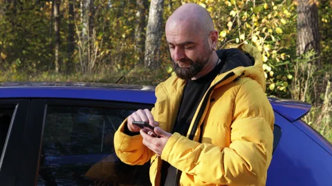 Bearded man in yellow jacket holding smartphone in his hands Stock Footage 163269260