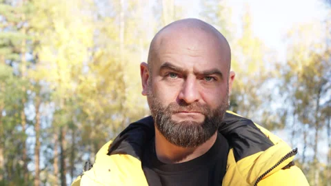 Bearded man in yellow jacket looking frowning outside in the autumn park Stock Footage 163267701