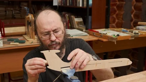 Bearded master measures outdated jetliner model details Stock Footage 127378118