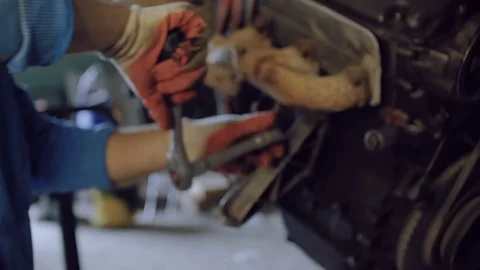 The bearded mechanic tightens the bolt with a tool on the hull of an automotive Stock Footage 78829756