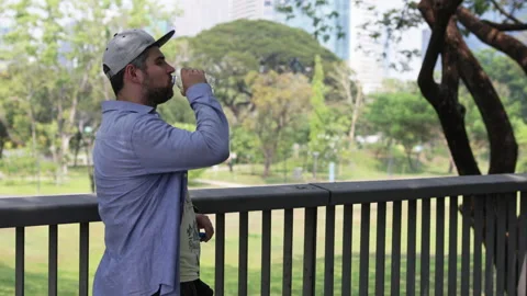 Bearded men in a cap drinking from bottle in park. Stock Footage 306647426